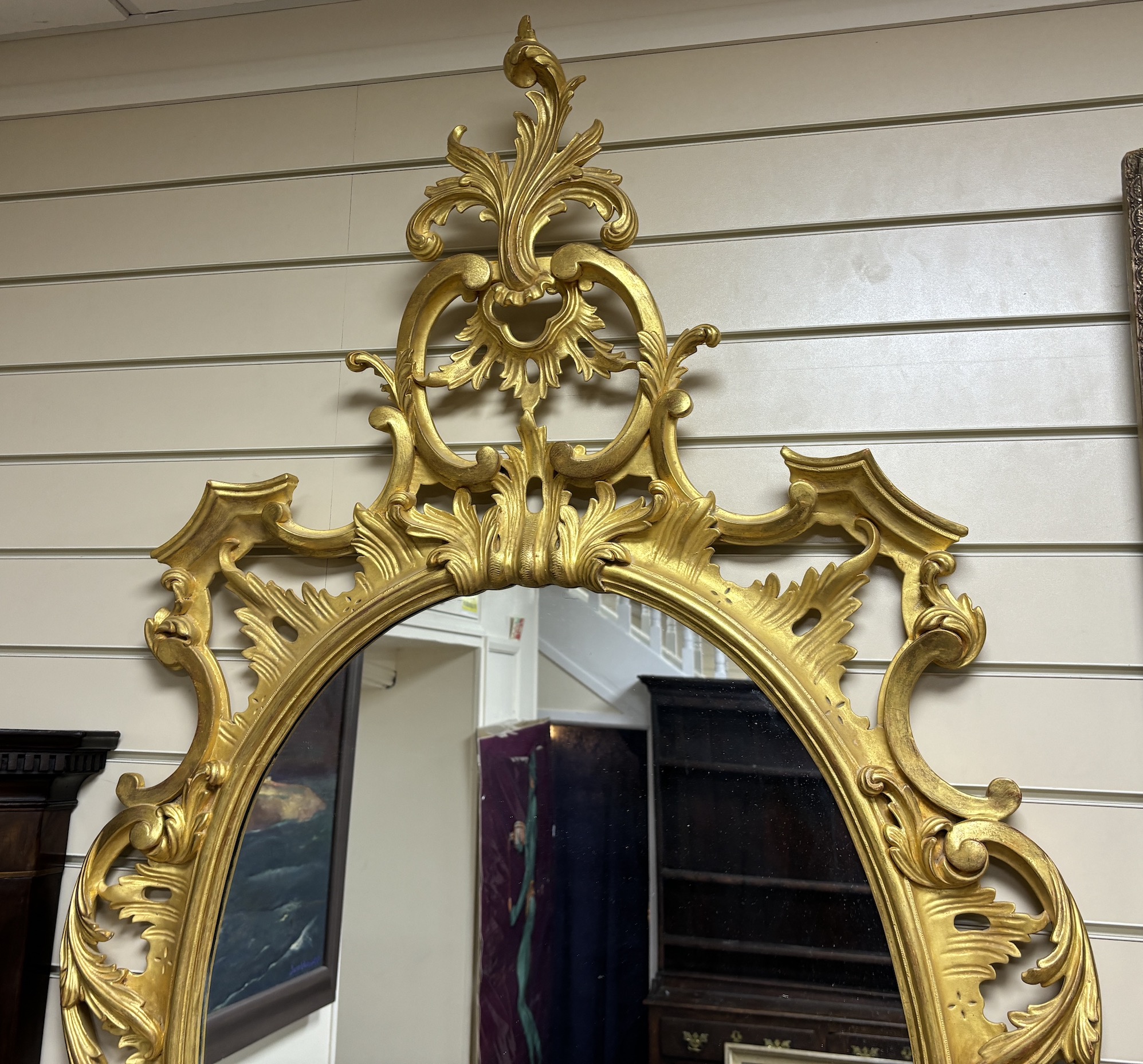 A George III style carved giltwood oval wall mirror, width 89cm, height 160cm